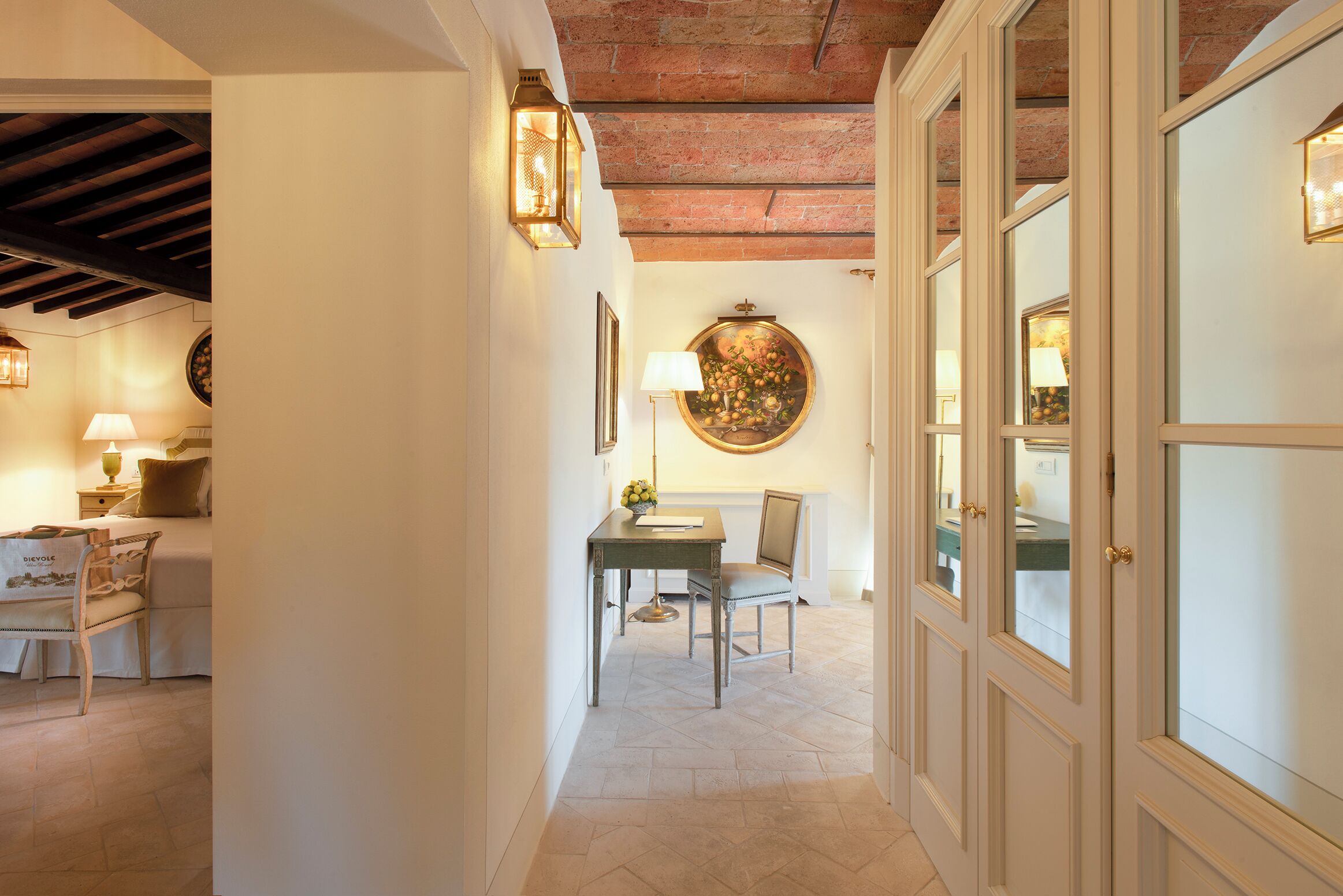 A hallway with a dining area, featuring a table and chairs, a lamp, and a wall-mounted painting.