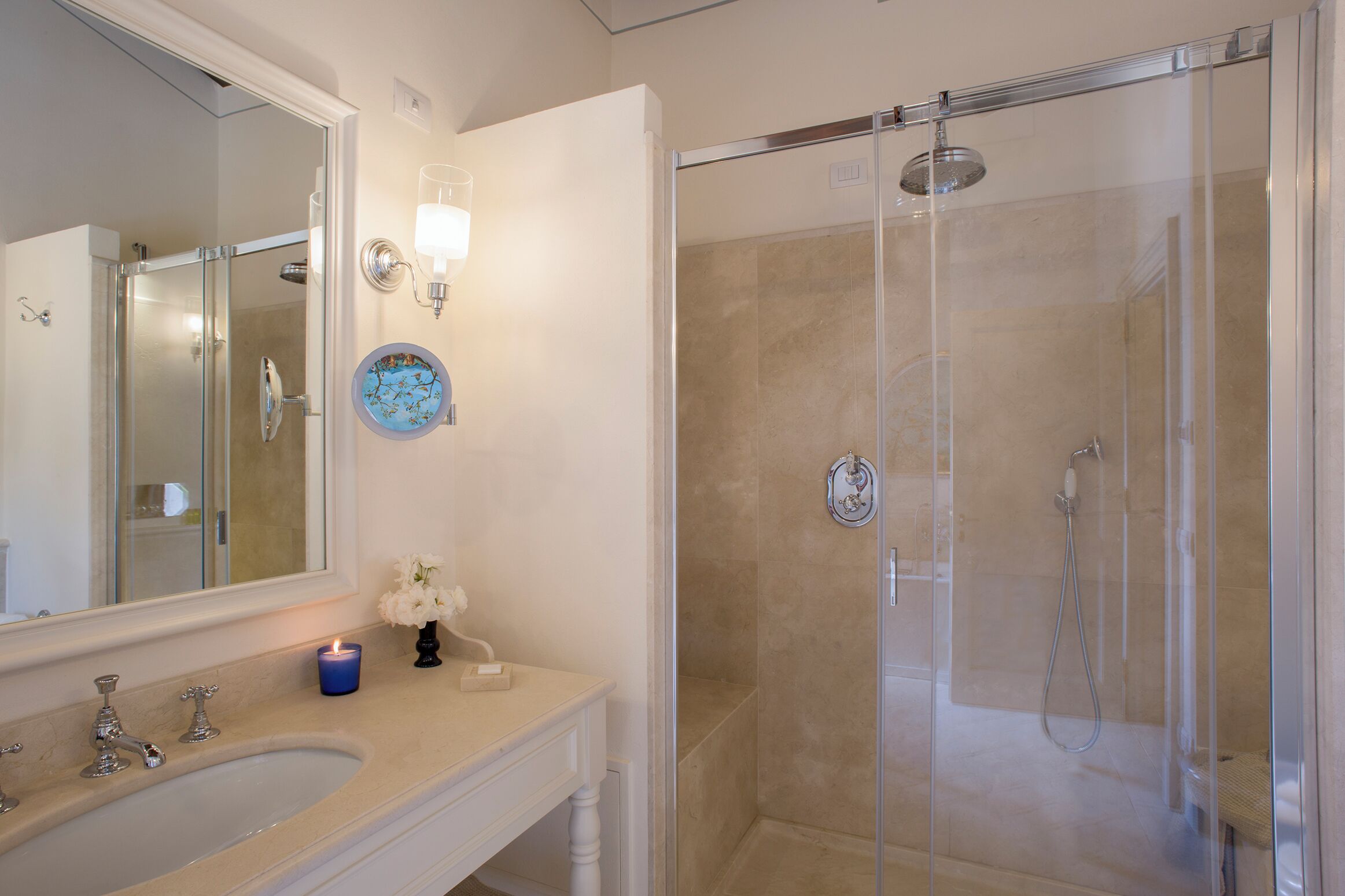 Une salle de bain dotée d’un grand miroir, d’un lavabo, d’une douche en verre et d’une assiette décorative posée sur le comptoir.