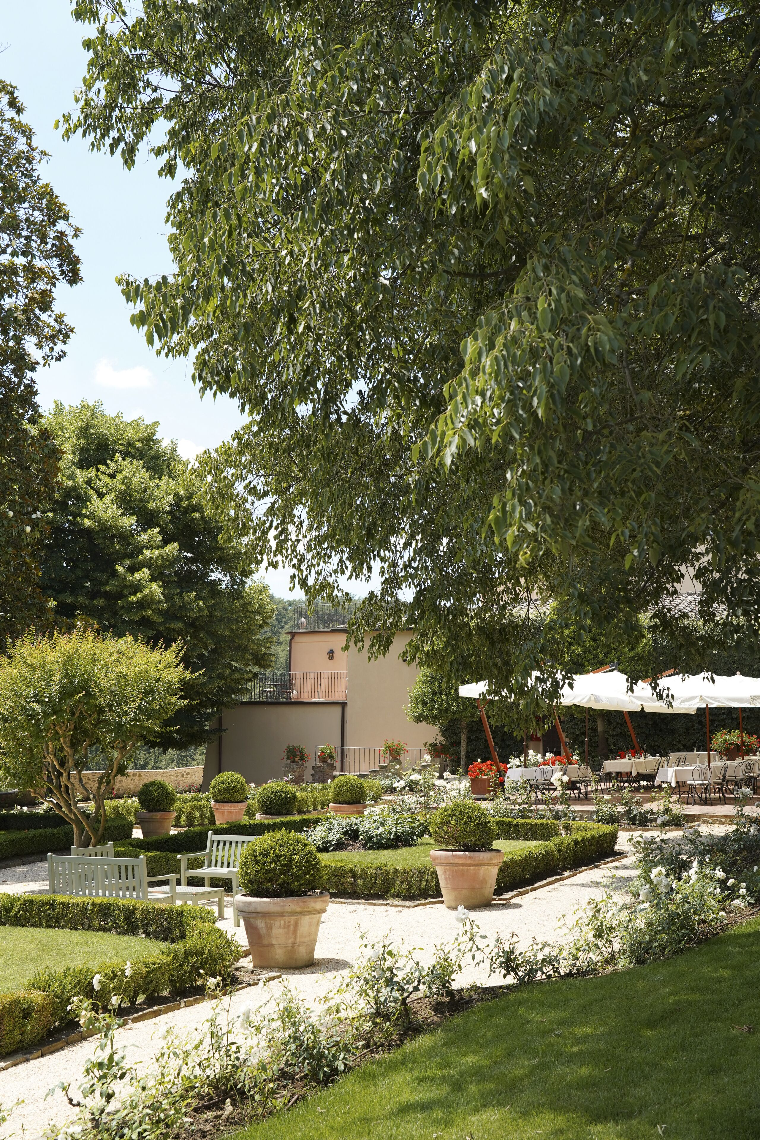 A garden with neatly trimmed hedges, potted plants, and outdoor seating.
