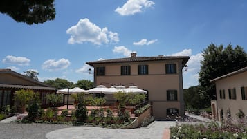 Un bâtiment doté d’une cour intérieure, d’un espace extérieur aménagé avec des parasols et d’un jardin fleuri.