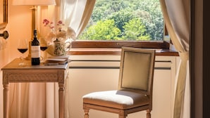 Ein Zimmer mit Blick auf einen Wald, ein Tisch mit Lampe und ein Stuhl.