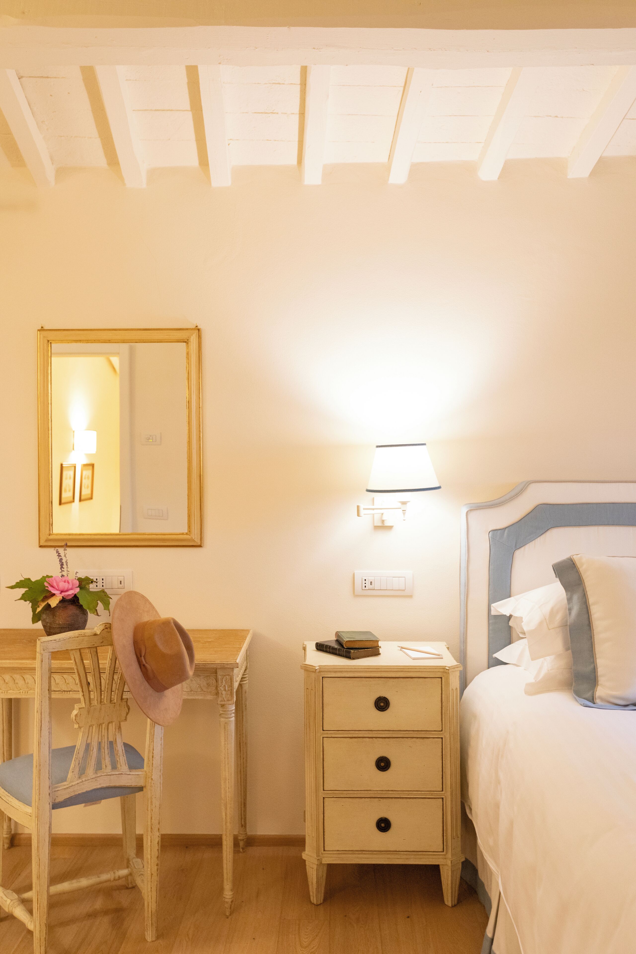 Une chambre à coucher comprenant un lit, une table de chevet, une chaise, un bureau et un miroir.