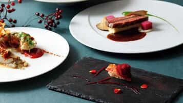 Three plates of gourmet dishes with a dark slate serving board in the foreground.