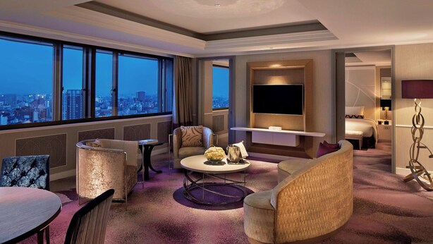 Una habitación de hotel moderna con vistas a la ciudad, un televisor de pantalla plana, una zona de estar cómoda y una cama.