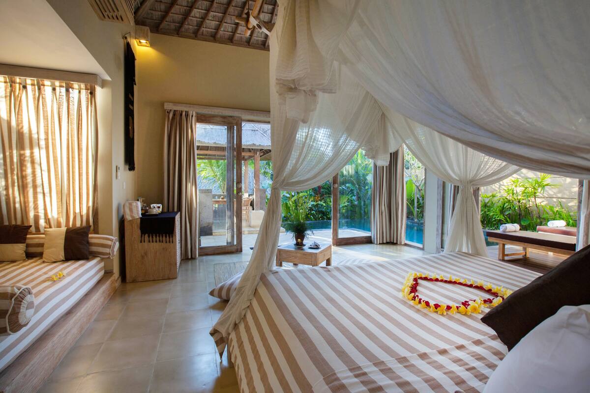 A bedroom with a large bed, a small table, and a bench.