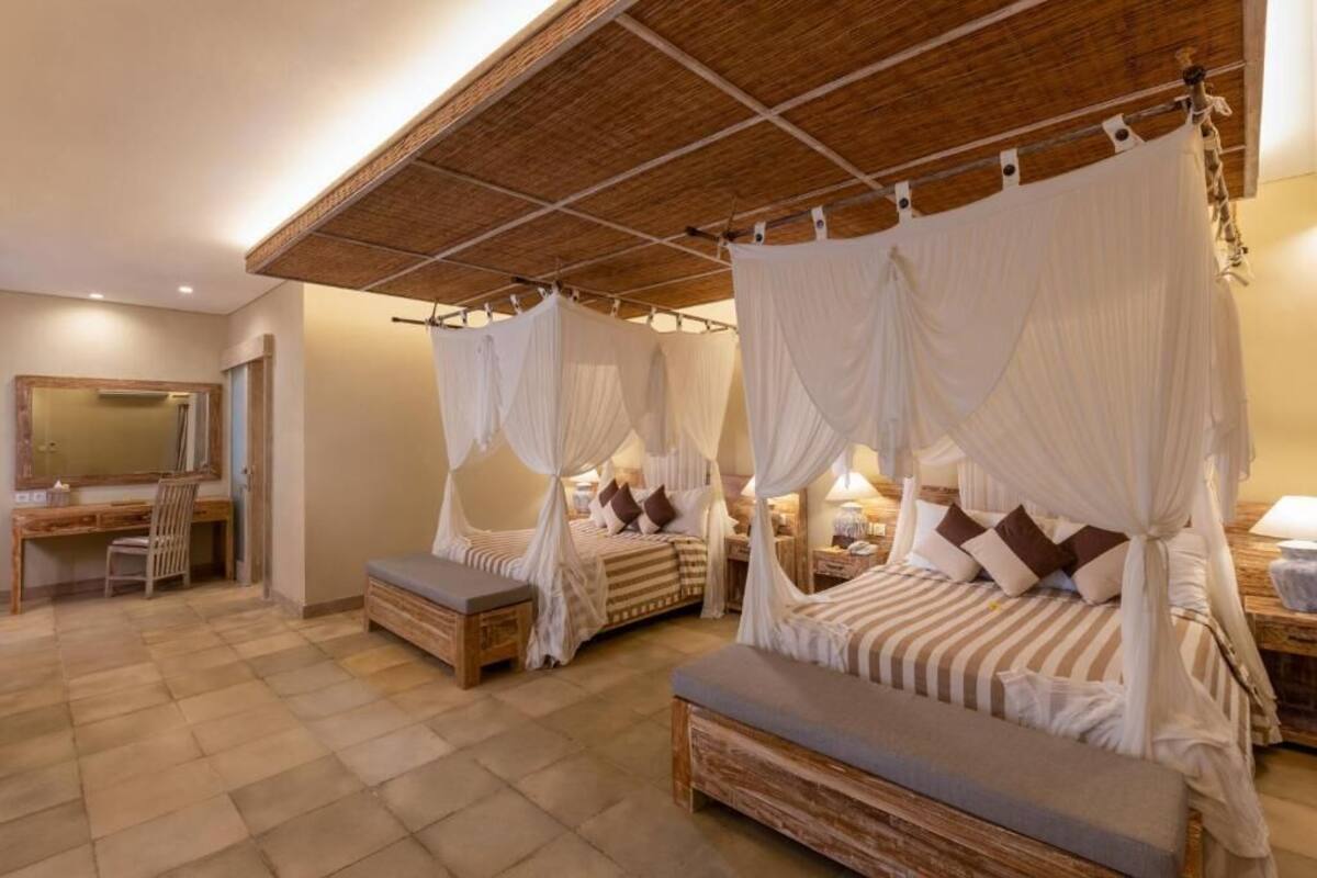 A bedroom with four beds, each with a canopy, a desk, and a chair.