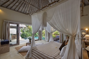 A bedroom with a canopy bed, a view of the pool, and a dining area.