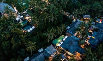 An aerial view of a resort with multiple bungalow-style buildings, a swimming pool, and lush tropical vegetation.