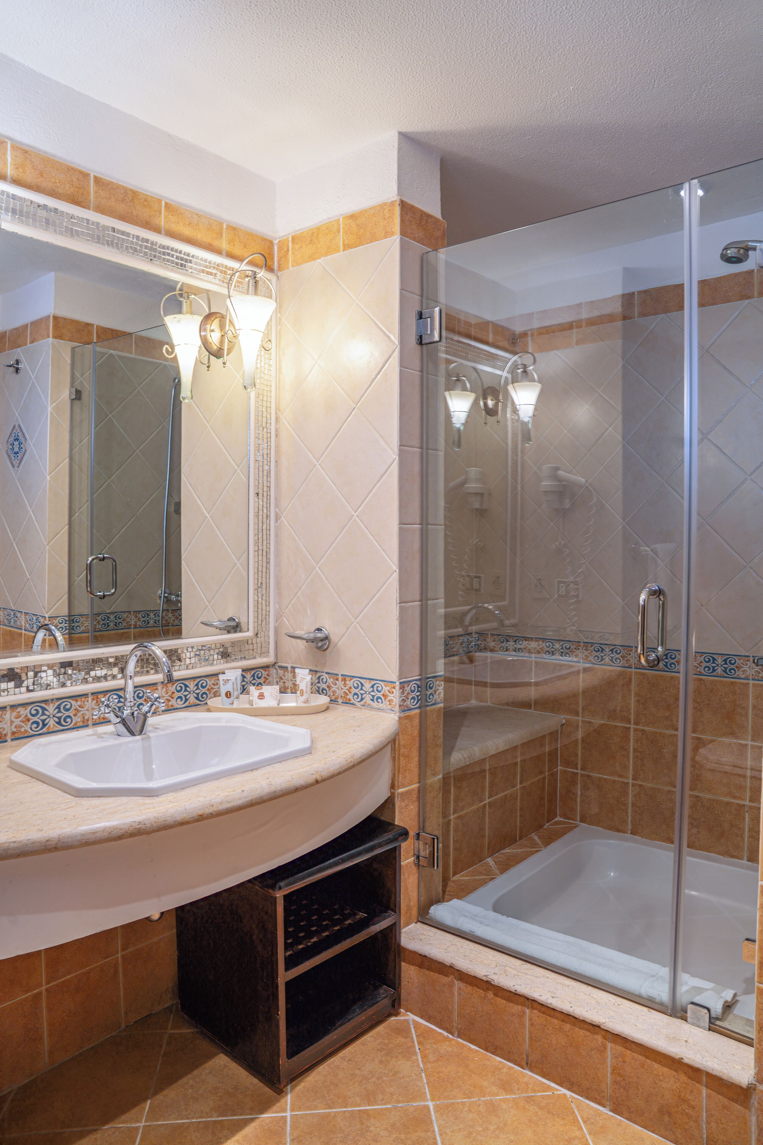 Un baño con ducha de vidrio, lavamanos y espejo.