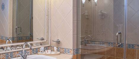 Un baño con ducha de vidrio, lavamanos y espejo.