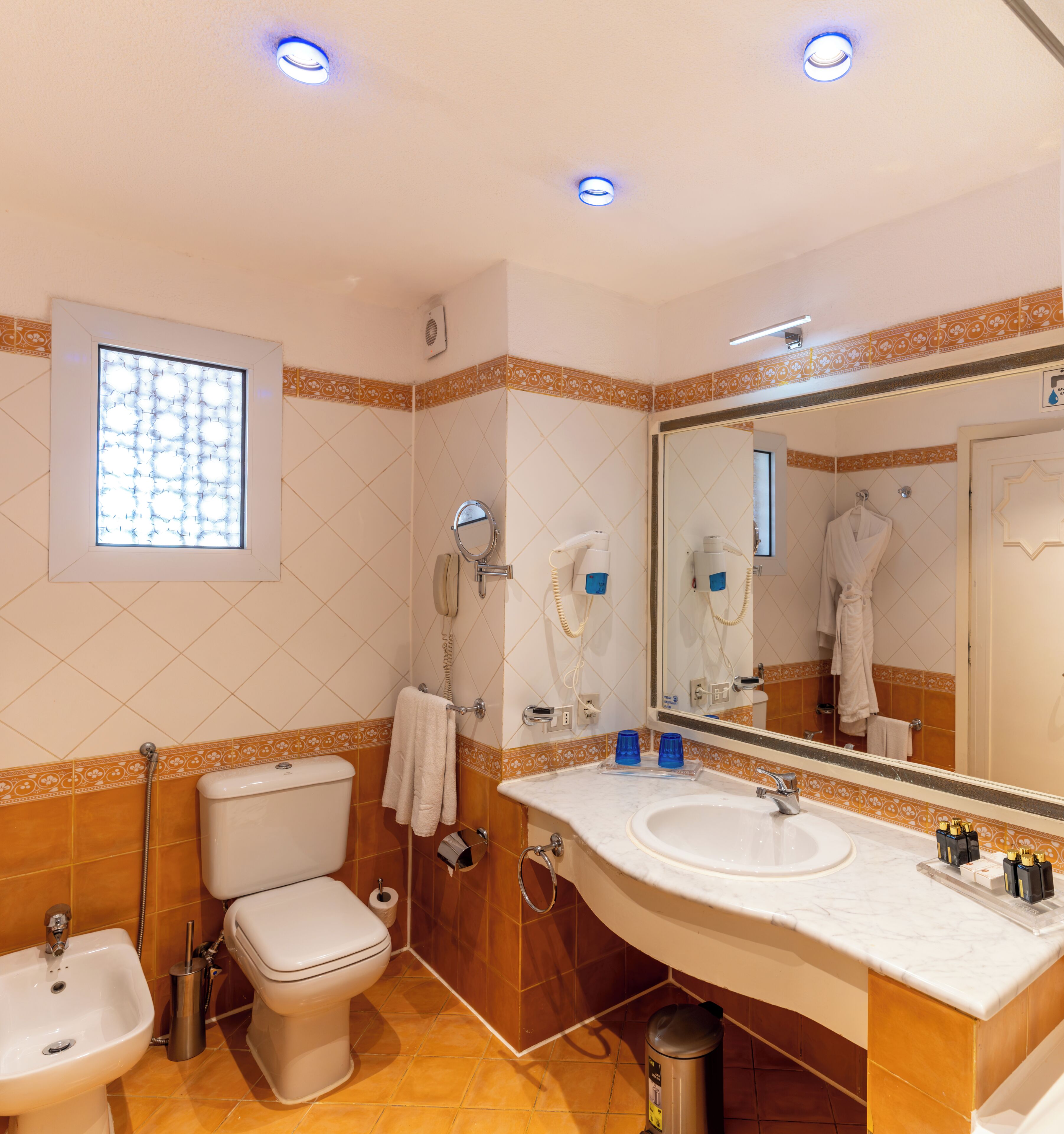 A bathroom with a toilet, bidet, sink, and mirror.