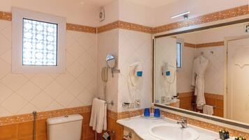 A bathroom with a toilet, bidet, sink, and mirror.