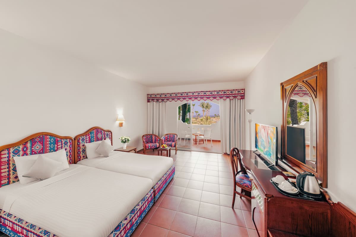 Une chambre d’hôtel avec deux lits, un coin repas et un téléviseur.