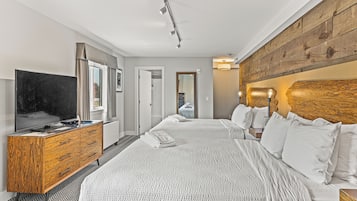 A modern hotel room with a large bed, a wooden dresser, a flat-screen TV, and a large mirror.