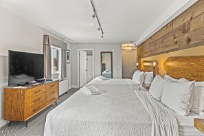Habitación de hotel moderna con una cama grande, un tocador de madera, un televisor de pantalla plana y un espejo amplio.