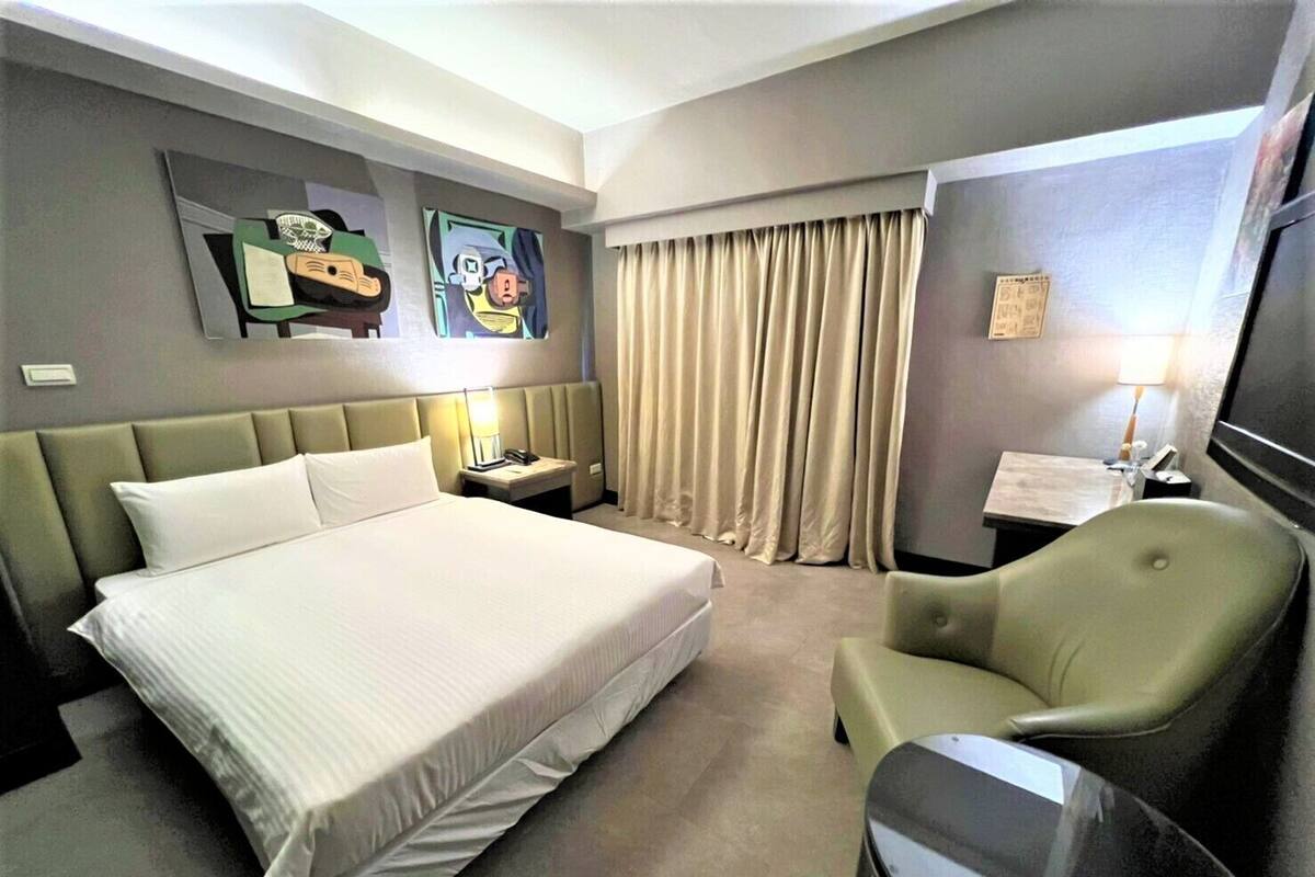 Une chambre d’hôtel avec un grand lit, un bureau, une chaise et un téléviseur.