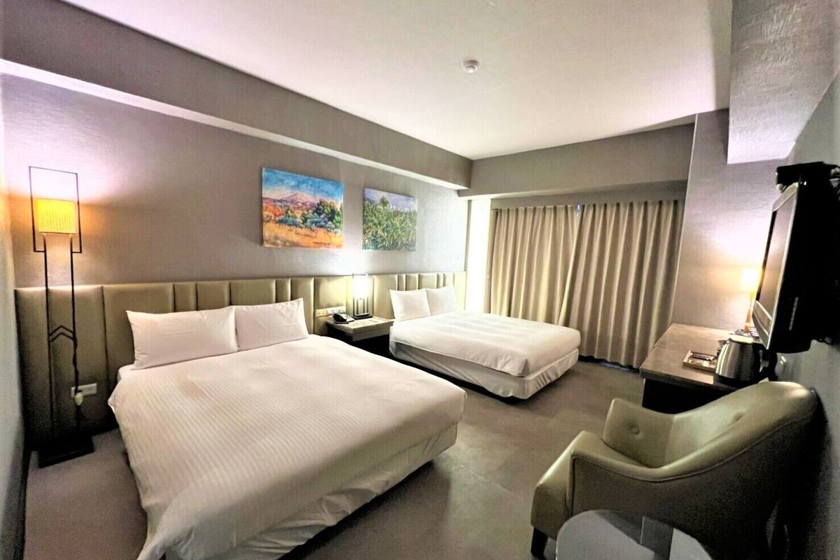 Une chambre d’hôtel avec deux lits, un bureau, une chaise et un téléviseur.