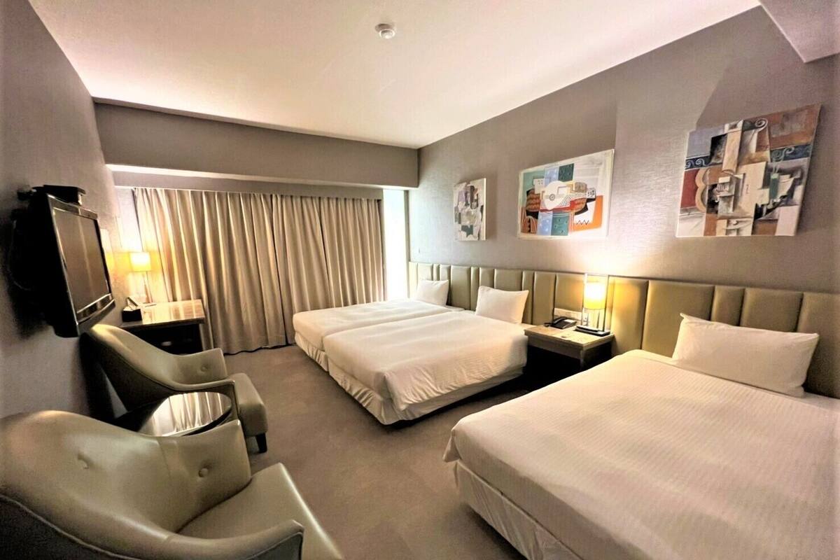 Une chambre d’hôtel avec deux lits, une télévision, un bureau et une chaise.