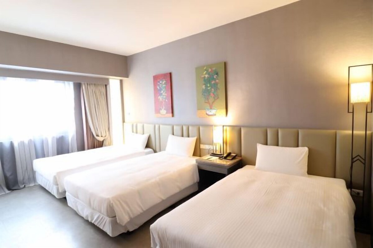 A hotel room with two beds, a nightstand, a lamp, and two wall art pieces.