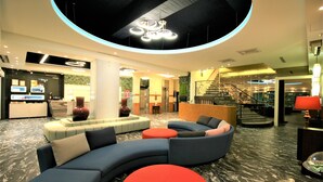 A modern lobby with a curved sofa, red ottoman, and a staircase. - Kaohsiung Ahotel (Kaohsiung)