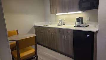 A compact kitchen with wooden cabinets, a built-in microwave, a coffee maker, and a sink.
