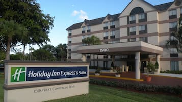 A Holiday Inn Express & Suites building with a sign indicating its address at 1500 West Commercial Blvd.