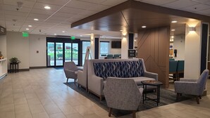 Eine Lobby mit Empfangstresen, Sitzgelegenheiten und einem großen Fenster.