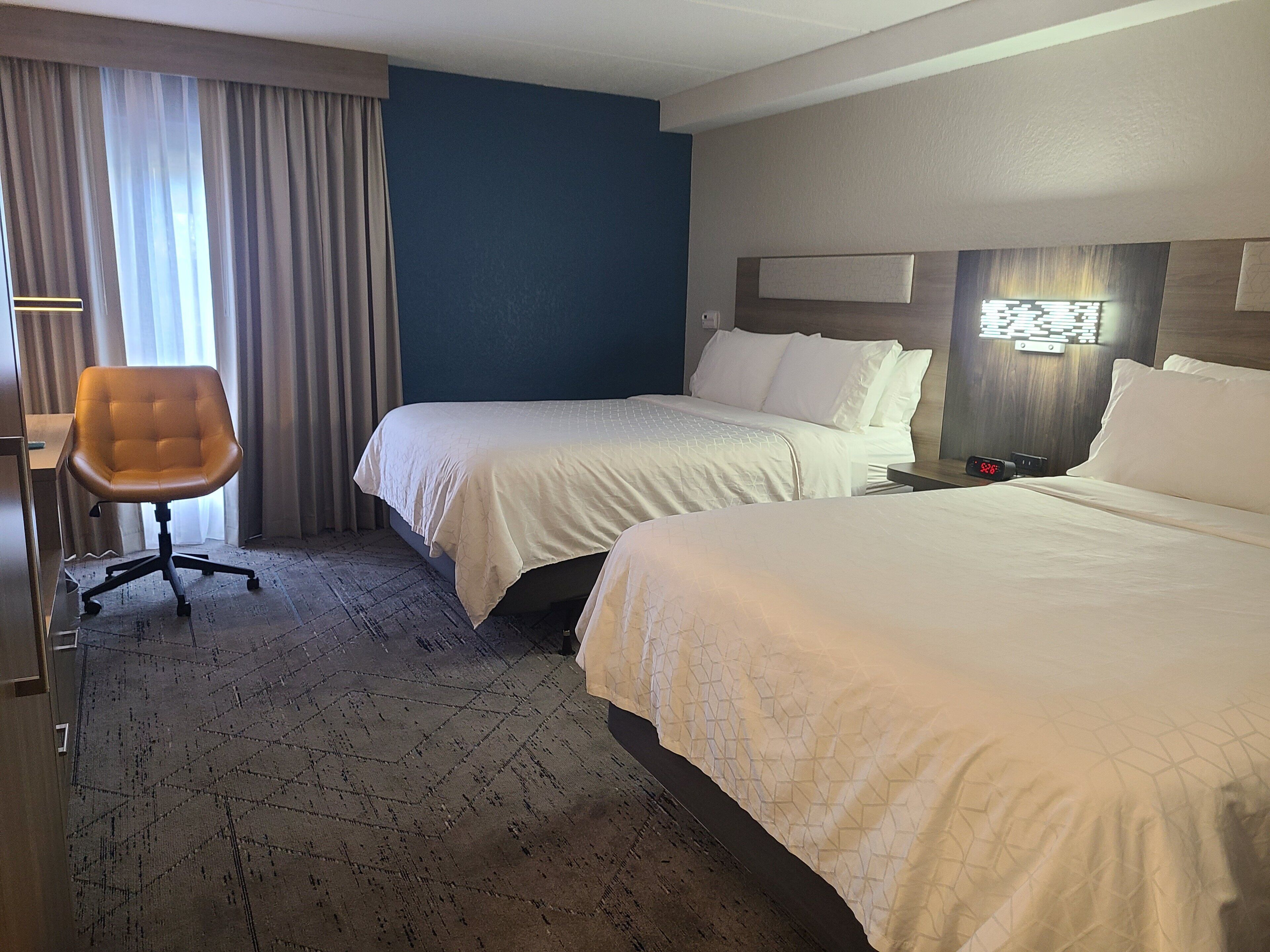 Een hotelkamer met twee bedden, een bureau en een stoel.