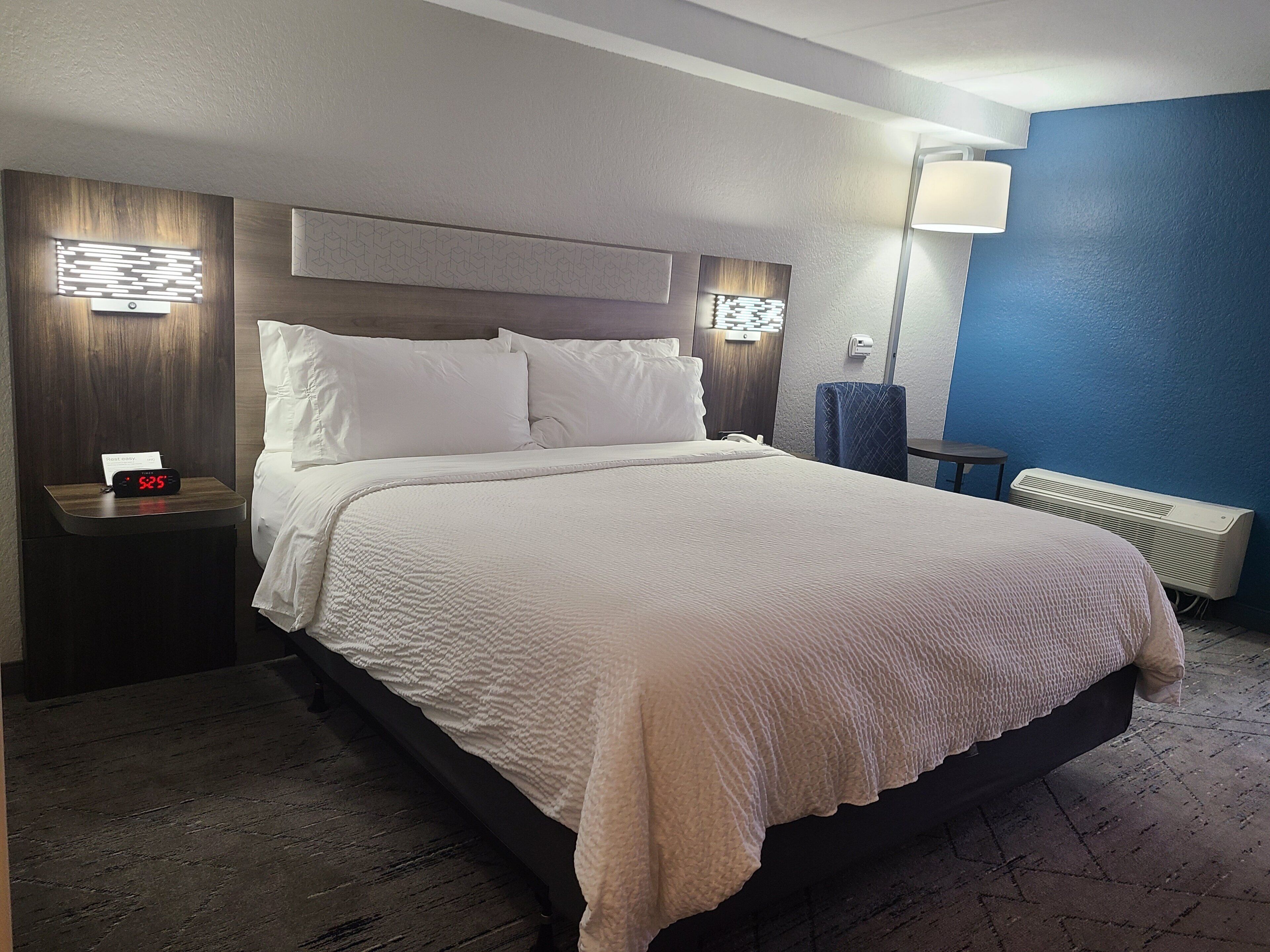 Une chambre d’hôtel avec un grand lit, des lampes de chevet, une table de nuit, un bureau et un radiateur fixé au mur.
