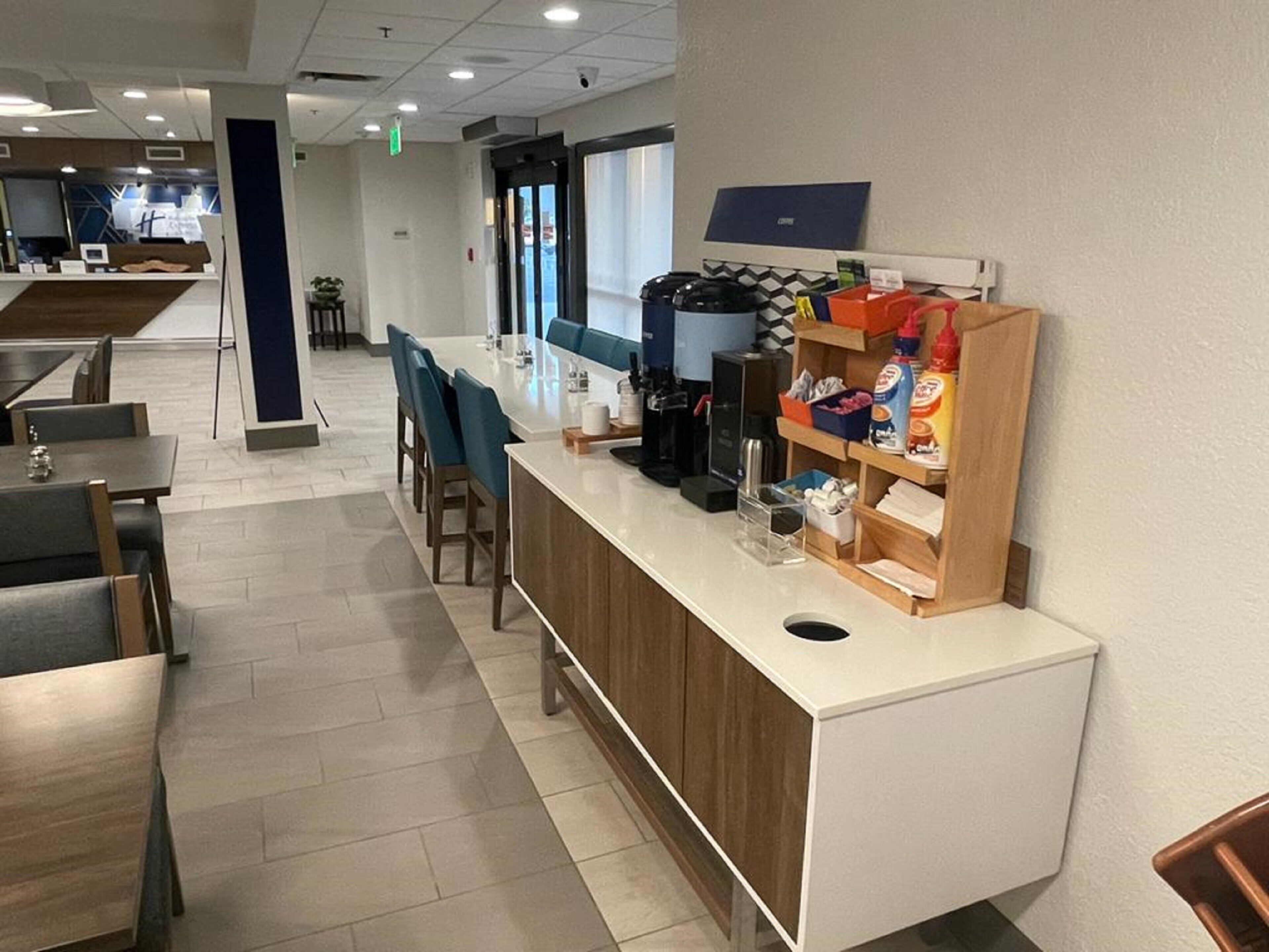 Un moderno vestíbulo de hotel con mostrador de recepción, zona de estar y estación de café.