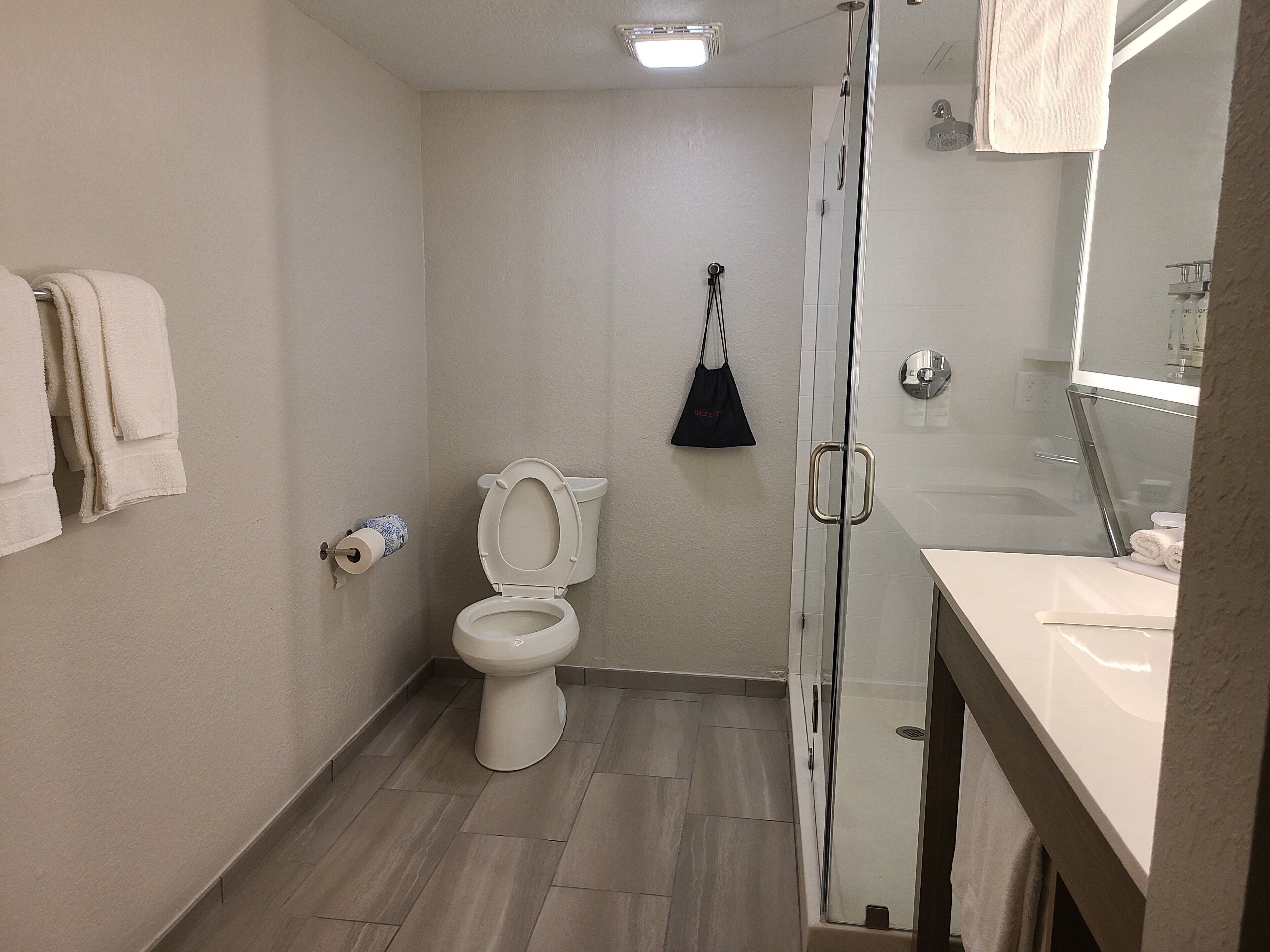 Un baño con inodoro, cabina de ducha de vidrio y lavabo con espejo.
