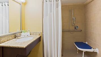 Une salle de bain avec une douche, un lavabo et un miroir.