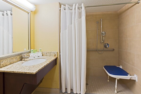 A bathroom with a shower, a sink, and a mirror.