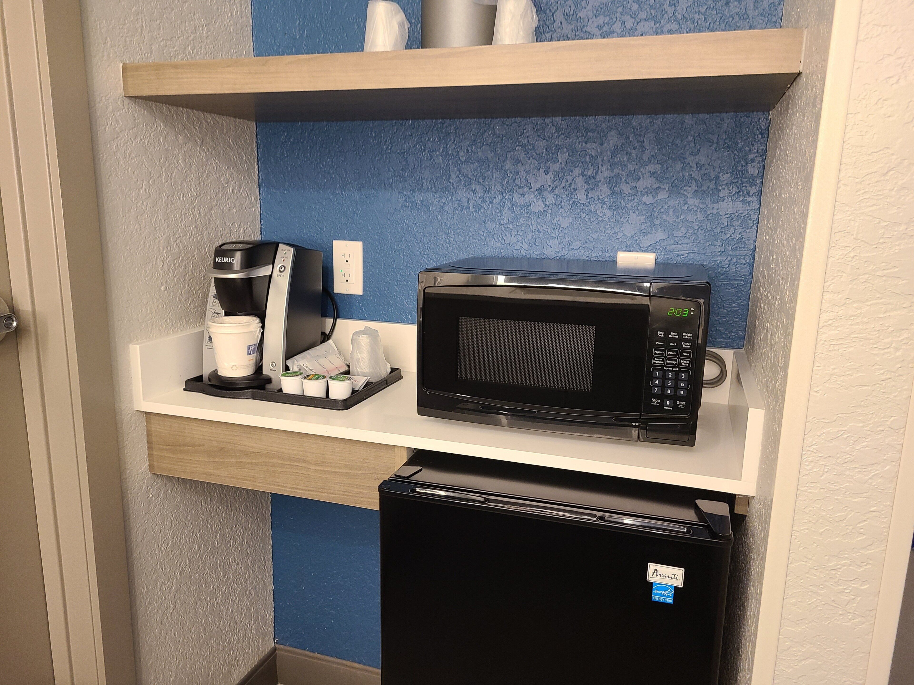 Una kitchenette equipada con cafetera, microondas y refrigerador.
