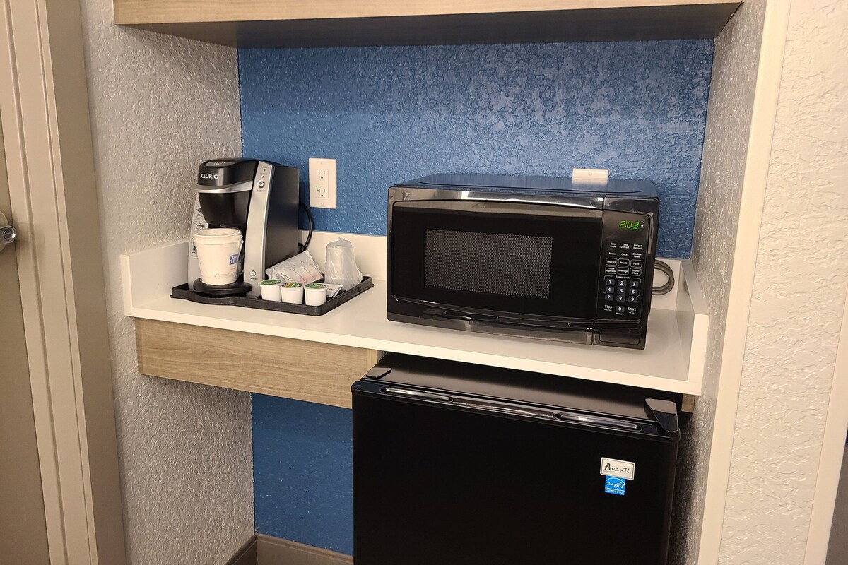 Una kitchenette equipada con cafetera, microondas y refrigerador pequeño.