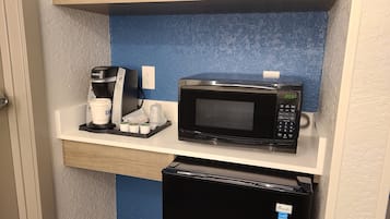 Una kitchenette equipada con cafetera, microondas y refrigerador.