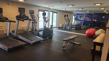 Ein Fitnessraum mit Laufbändern, Crosstrainern, einer Bank und Trainingsbällen.
