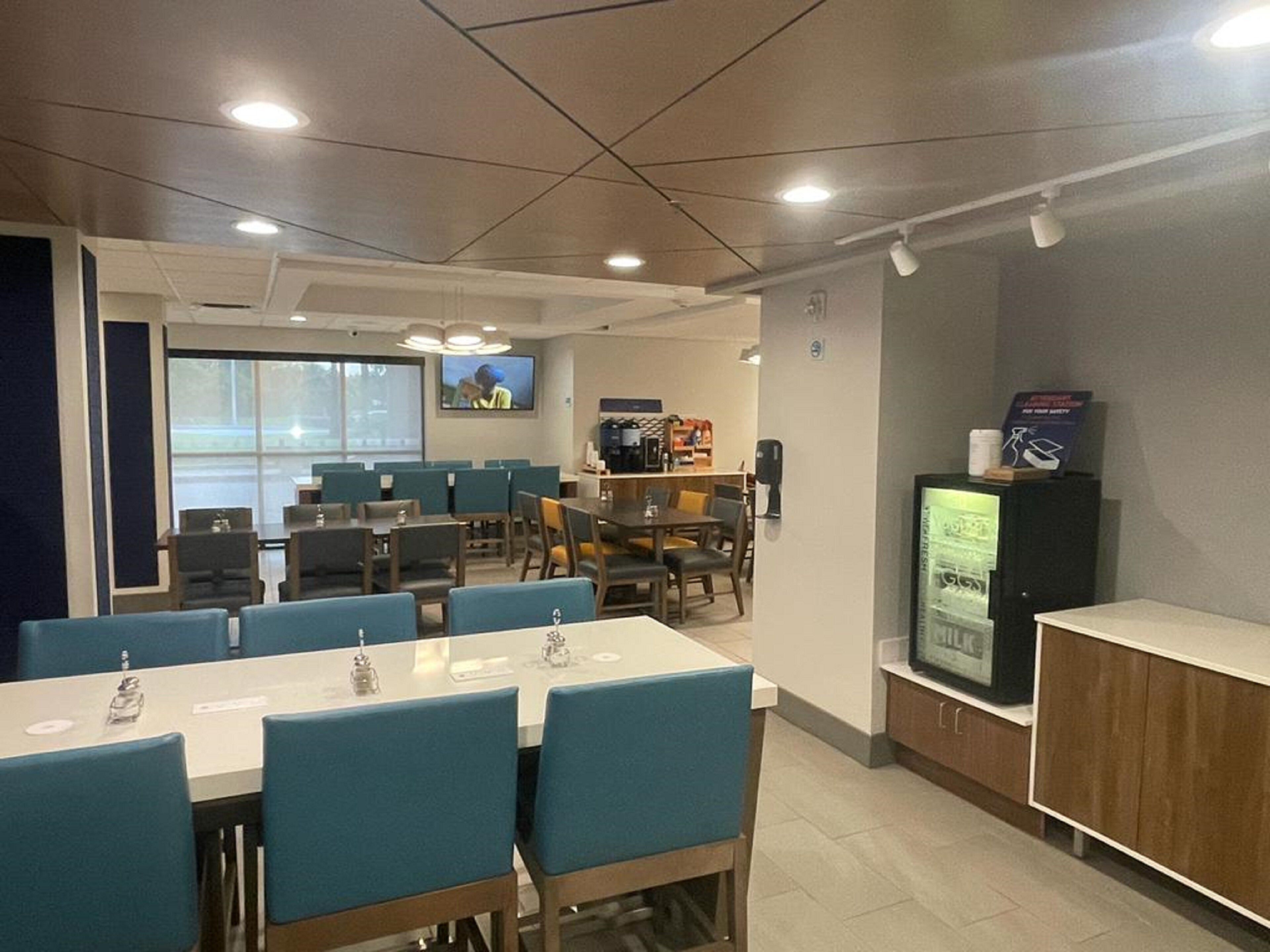 A conference room with tables and chairs, a television, and a vending machine.