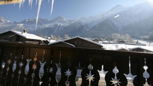 A mountain view with snow-covered houses and icicles hanging from the roof. - Hôtel Chris-tal (Les Houches)