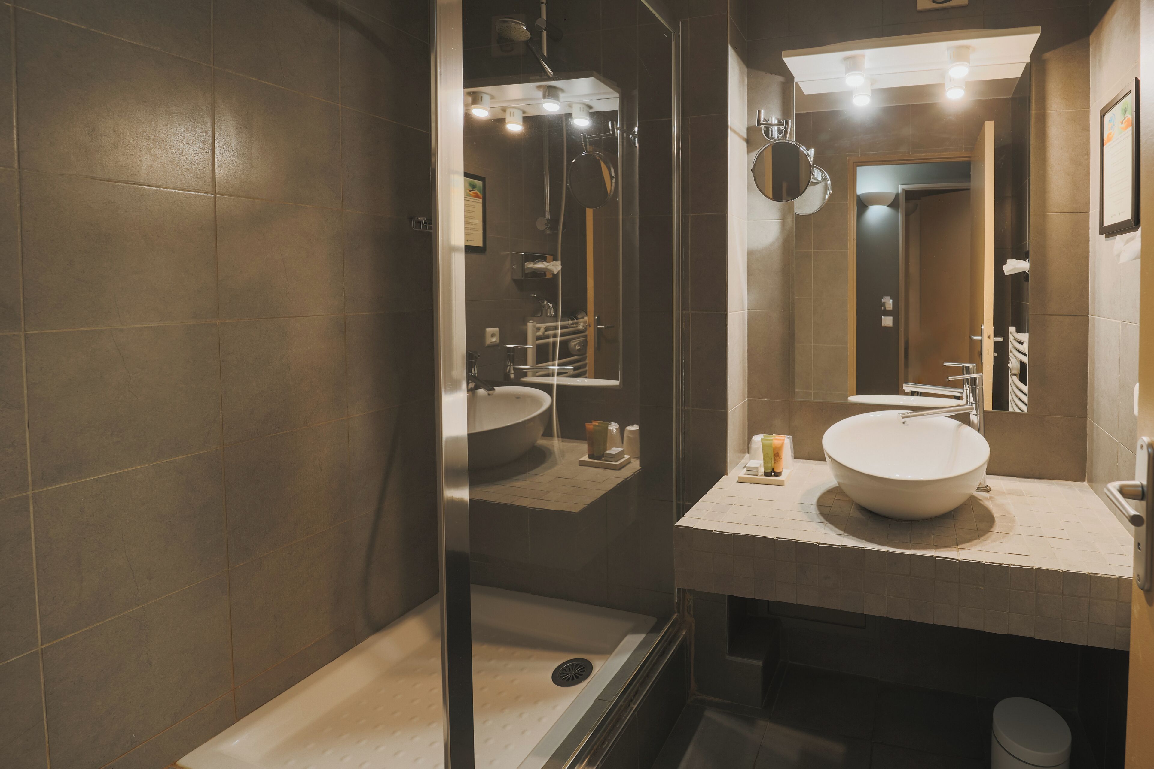 Une salle de bain moderne avec un grand lavabo, un miroir et un espace douche.
