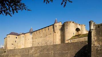 A large, historic stone castle with multiple towers and a thick stone wall.