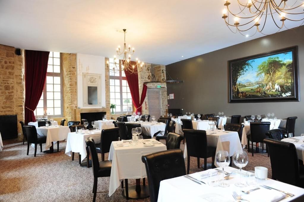 A dining area with multiple tables, chairs, and a chandelier.