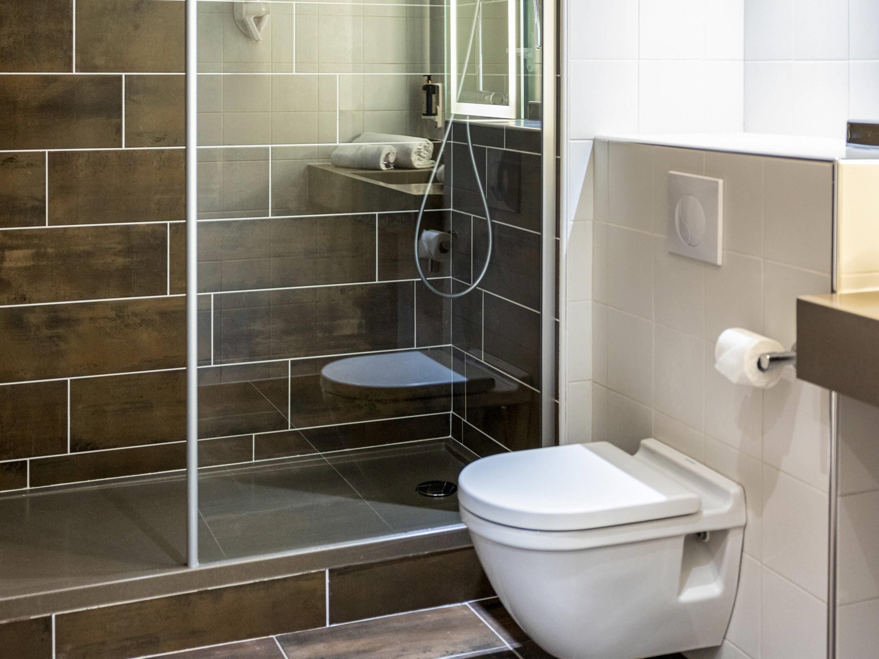 Et moderne badeværelse med bruser, toilet og et bruseområde med glasvægge.