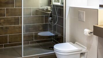 Et moderne badeværelse med bruser, toilet og et bruseområde med glasvægge.