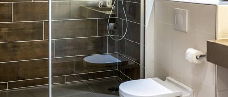 Un baño moderno con ducha, inodoro y cabina de ducha acristalada.