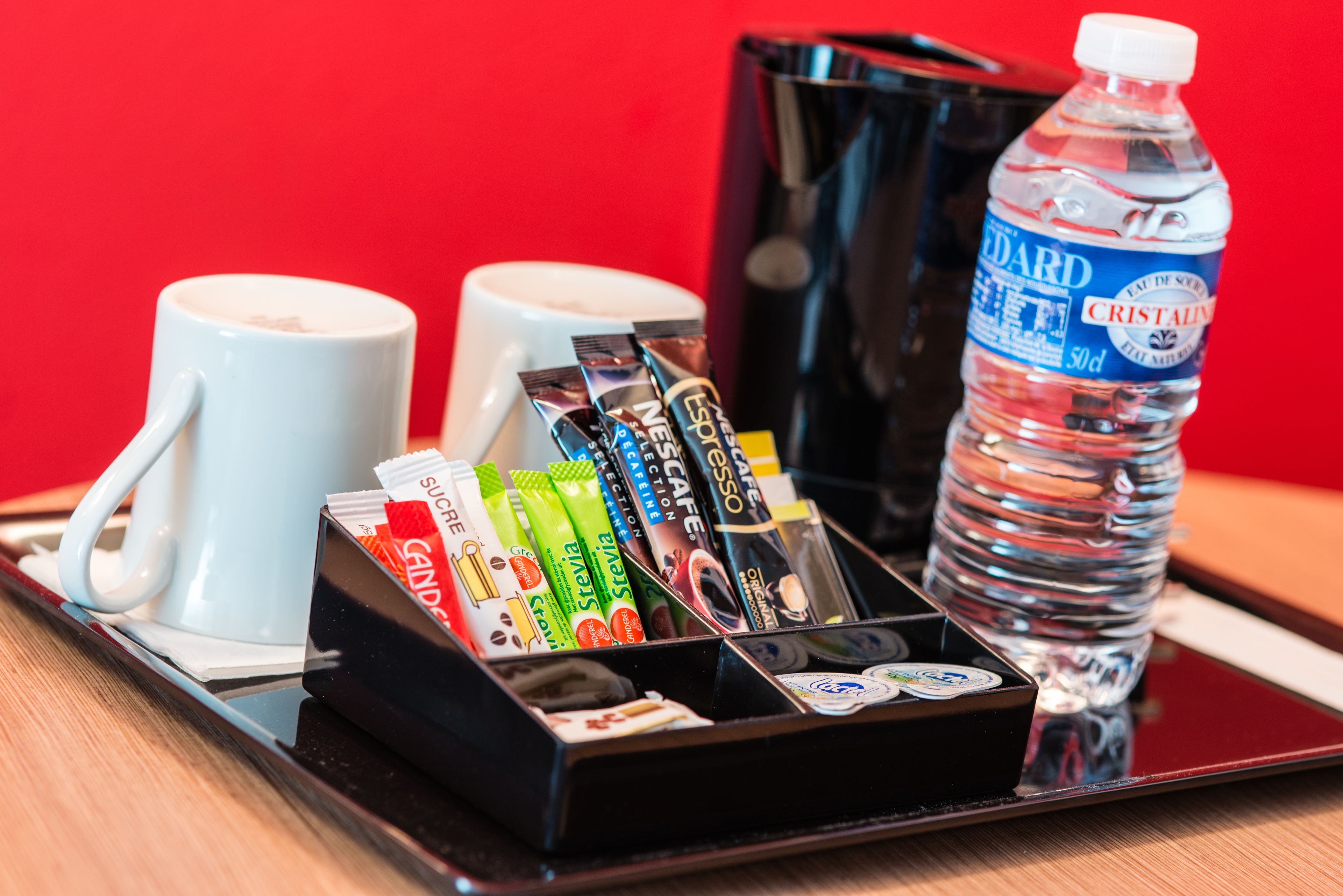 Ein Tablett mit einer Wasserflasche, zwei Kaffeetassen und einer Auswahl an Kaffee-Nachfüllpackungen.