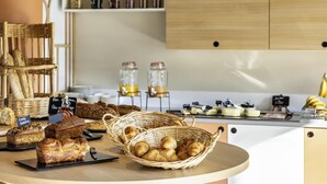 A bakery display with various breads and pastries, a wicker basket with croissants, and jars of preserves on shelves. - Mercure Agen Centre (Agen)