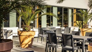 An outdoor seating area with tables and chairs, surrounded by large potted plants. - Mercure Agen Centre (Agen)