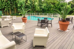 A poolside area with outdoor seating, a pool, and surrounding greenery. - Mercure Agen Centre (Agen)