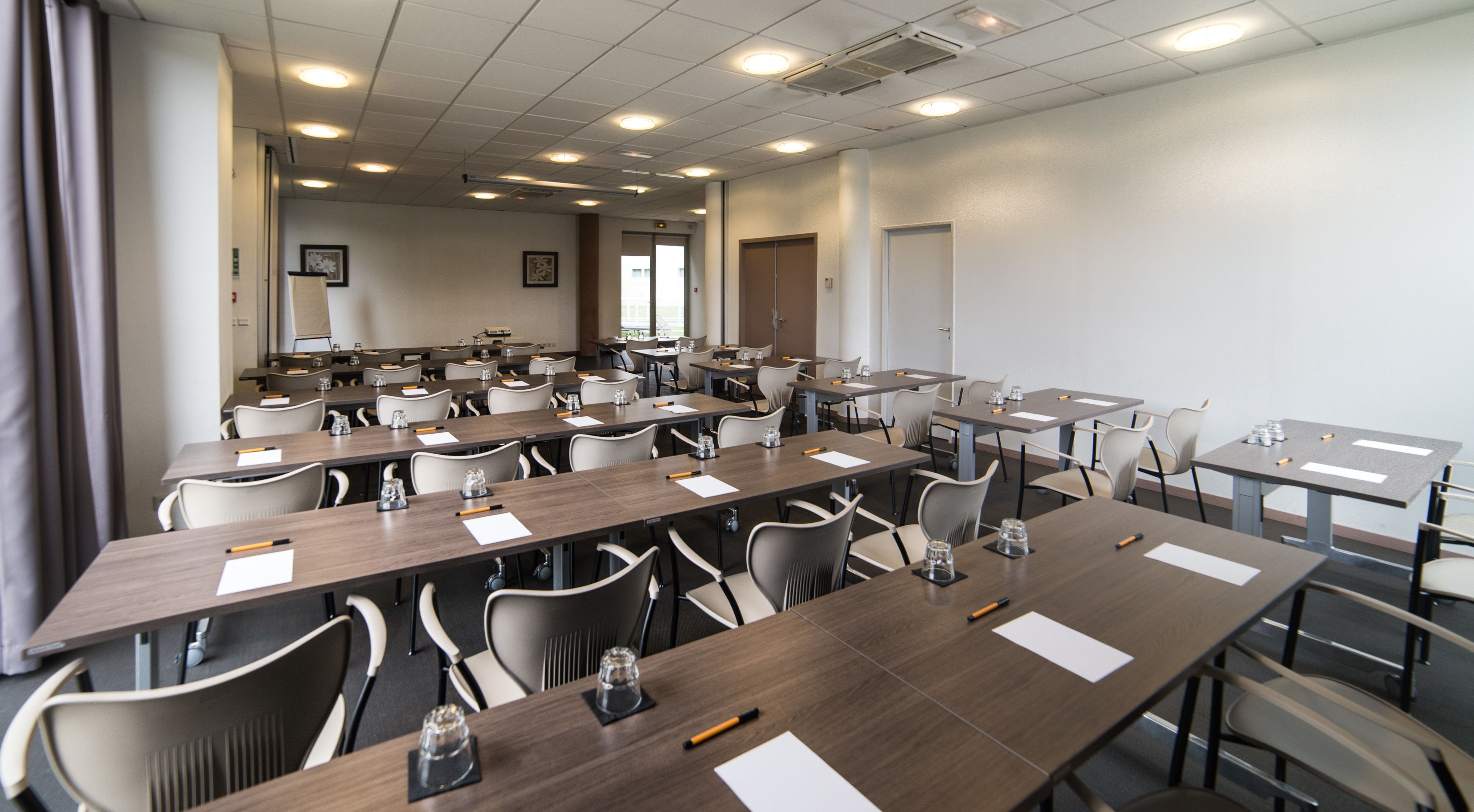 Une salle de conférence dotée de plusieurs tables et chaises, ainsi que de bouteilles d’eau et de stylos.